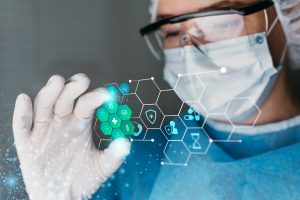 A doctor wearing protective eyewear and a PPE kit interacting with a holographic icon